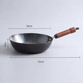 A hammered metal wok with a brown leather-wrapped handle, shown on a light gray background with overlaid dimension lines and text indicating 28 cm width, 7 cm depth, and 50 cm total length.