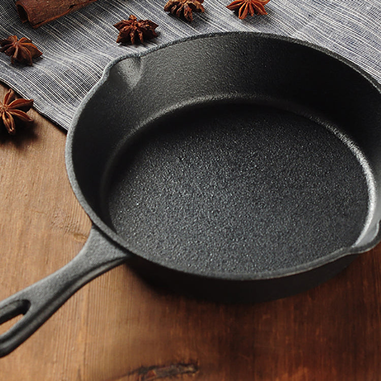 Cast iron skillet on a wooden surface with star anise and cinnamon sticks.